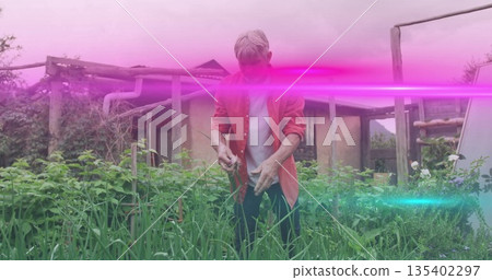 Grasping plants gardener wearing red shirt over white tee tending backyard garden with pergola shed Grasping plants gardener wearing red shirt over white tee tending backyard garden with pergola shed 135402297