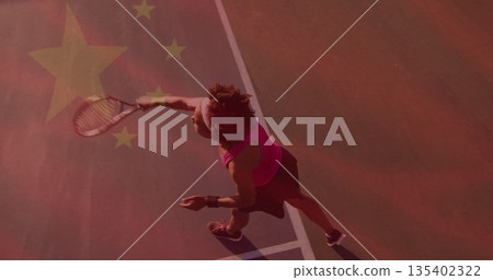 Swinging female tennis player hitting ball with racket on red hard court with lines, star overlay 135402322
