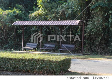 Dark brown metal bus shelter standing quietly outdoors Dark brown metal bus shelter standing quietly outdoors 135402452