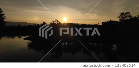 Sunset over river with mountains in the background Sunset over river with mountains in the background 135402514