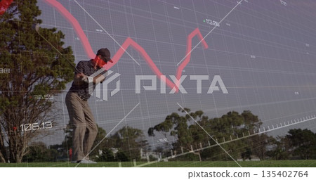 Swinging light-skinned mid-adult male golfer driving ball off tee box, with financial chart overlay 135402764
