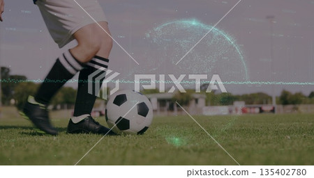 Dribbling female player controlling ball on grass field in neon cleats, with green digital overlay 135402780