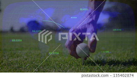 Golfer hand positioning golf ball on tee on trimmed grass, showing world map overlay, copy space 135402874