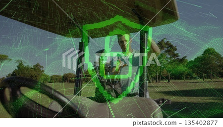 Standing adult male golfer holding smartphone on golf cart on fairway, with digital shield overlay 135402877