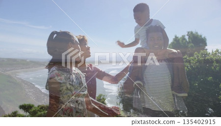 Walking family carrying son on shoulders along coastal bluff path, with ocean view, floral sundress 135402915