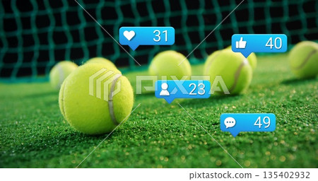 Displaying tennis balls resting on green turf court by net with social media notification icons Displaying tennis balls resting on green turf court by net with social media notification icons 135402932