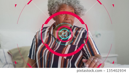 Senior woman wearing striped shirt using AR interface with pillow, blanket, table in bedroom Senior woman wearing striped shirt using AR interface with pillow, blanket, table in bedroom 135402934