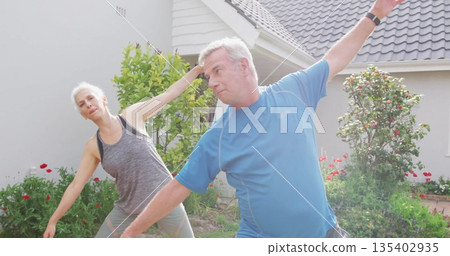 Stretching couple wearing athletic wear doing side stretches on grass lawn, with fitness tracker Stretching couple wearing athletic wear doing side stretches on grass lawn, with fitness tracker 135402935