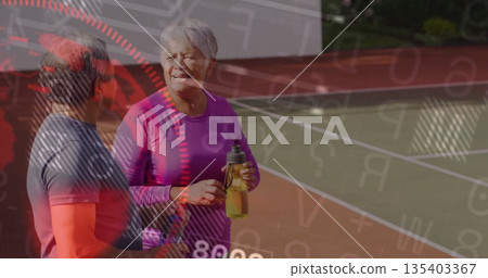 Chatting senior pair in sportswear on tennis court, with white boundary lines and water bottle Chatting senior pair in sportswear on tennis court, with white boundary lines and water bottle 135403367