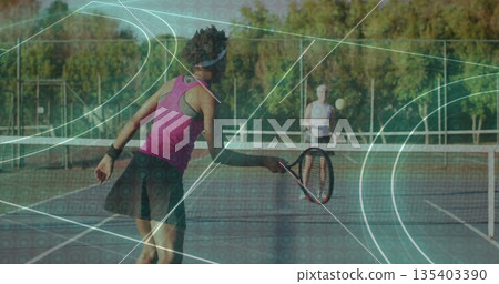 Swinging racket tennis player wearing pink tank top hitting ball over net on hardcourt, copy space 135403390