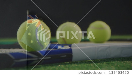 Displaying tennis racket with white grip and three yellow balls on artificial-grass court, gear 135403430