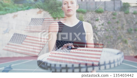 Standing tennis player in black sportswear holding racket on court with American flag overlays Standing tennis player in black sportswear holding racket on court with American flag overlays 135403442