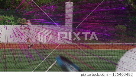 Serving man in white tennis attire hitting ball on private backyard tennis court, with tennis net 135403493