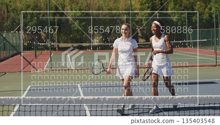 Walking women wearing tennis attire carrying tennis rackets across tennis court, with net and fence Walking women wearing tennis attire carrying tennis rackets across tennis court, with net and fence 135403548