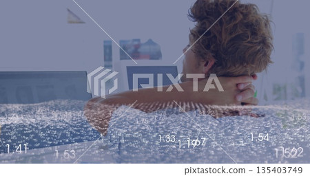 Leaning back man analyzing data on screens at office desk, with laptop and monitor, copy space 135403749