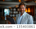 Smiling Businessman In Light Suit Holding Tablet Device 135403861