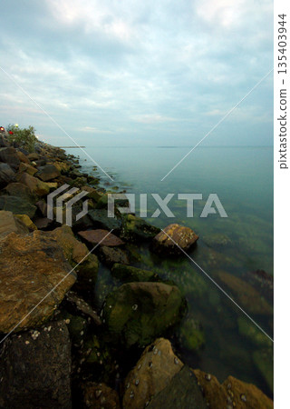 Soft waves on a rocky beach in the evening Soft waves on a rocky beach in the evening 135403944