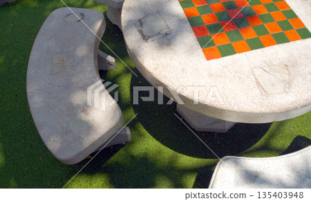 A chessboard made of tiles on the top of a garden concrete table 135403948