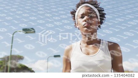 Standing athlete wearing white tank and headband on track, with binary overlay and tall poles 135404082