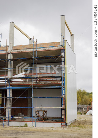 Workers continue construction of a building with scaffolding around it. The scene shows walls being erected and materials on site Workers continue construction of a building with scaffolding around it. The scene shows walls being erected and materials on site 135404143