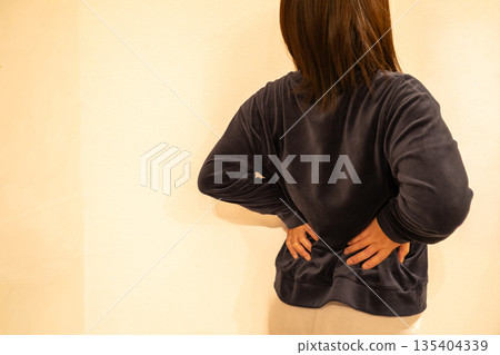 A woman who puts her hand on her waist with back pain A woman who puts her hand on her waist with back pain 135404339