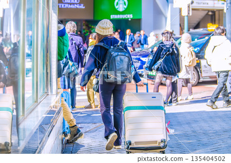Suitcases in the Tokyo cityscape of Japan. Inbound tourism continues... A couple of foreign tourists at the side of Shibuya Scramble Crossing... 135404502