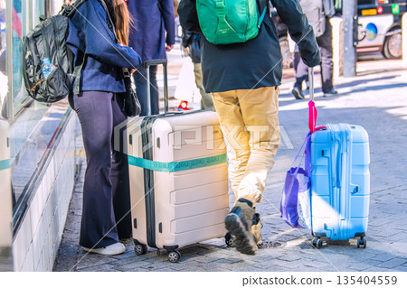 日本東京的城市景觀中隨處可見的行李箱。入境旅遊仍在繼續…一對外國遊客站在澀谷十字路口旁… 135404559