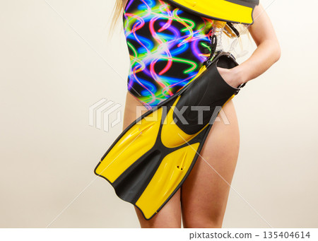 Woman in swimsuit holds flippers Woman in swimsuit holds flippers 135404614