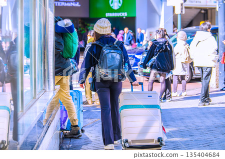日本東京的城市景觀中隨處可見的行李箱。入境旅遊仍在繼續…一對外國遊客站在澀谷十字路口旁… 135404684
