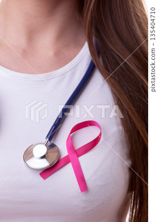 Pink ribbon and stethoscope on female chest 135404710
