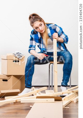 Woman moving into apartment assembly furniture. 135404720