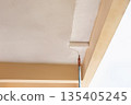 Painter using a roller to apply fresh white paint to a ceiling. 135405245