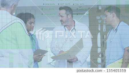 Medical team in uniforms discussing chart in hospital corridor with tablet and stethoscopes Medical team in uniforms discussing chart in hospital corridor with tablet and stethoscopes 135405359