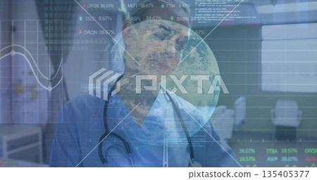 Standing medic in blue scrubs and stethoscope reviewing charts and globe at consultation desk Standing medic in blue scrubs and stethoscope reviewing charts and globe at consultation desk 135405377