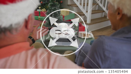 Grandparents wearing Santa hat calling grandchild on laptop at coffee table, with Xmas tree, gifts Grandparents wearing Santa hat calling grandchild on laptop at coffee table, with Xmas tree, gifts 135405494