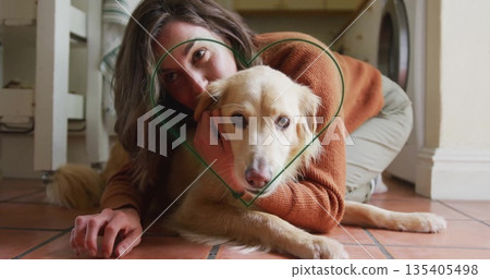 Hugging female adult wrapping arm around cream-colored dog on terracotta tile floor, with washer Hugging female adult wrapping arm around cream-colored dog on terracotta tile floor, with washer 135405498