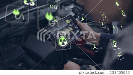 Examining mechanic's hands holding tablet computer at auto repair workshop bay, with energy icons Examining mechanic's hands holding tablet computer at auto repair workshop bay, with energy icons 135405633