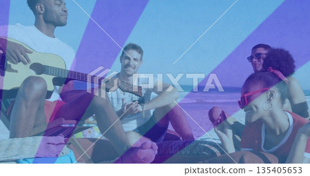 Strumming acoustic guitar, five friends sitting at beach shore, holding popsicles and sunglasses 135405653