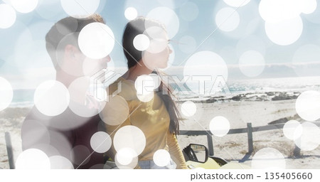 Gazing romantic couple sitting in yellow convertible on sandy shoreline, with wooden guardrail Gazing romantic couple sitting in yellow convertible on sandy shoreline, with wooden guardrail 135405660
