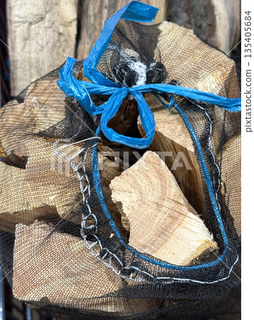 Chopped firewood in a mesh bag for storage and transport. Chopped firewood in a mesh bag for storage and transport. 135405684