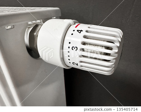 Close-up of a white radiator thermostat in a home setting. Close-up of a white radiator thermostat in a home setting. 135405714