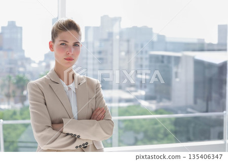 Professional woman standing at glass railing on balcony overlooking city wearing jacket, copy space Professional woman standing at glass railing on balcony overlooking city wearing jacket, copy space 135406347