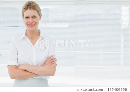 Female professional standing confidently in office under horizontal blinds wearing white blouse 135406366