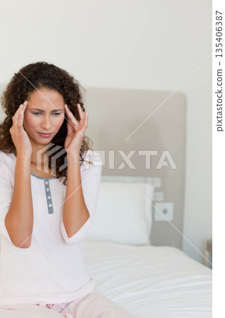 African American woman sitting on bed edge pressing temples in bedroom with headboard power outlet African American woman sitting on bed edge pressing temples in bedroom with headboard power outlet 135406387
