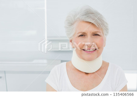 Senior female patient sitting in clinic room wearing cervical collar and pearl earrings, copy space 135406566
