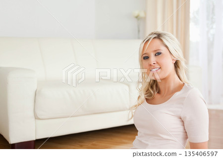 White female wearing pink top sitting at home before white sofa under sheer curtain, copy space White female wearing pink top sitting at home before white sofa under sheer curtain, copy space 135406597