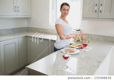 Woman cutting greens on granite countertop next to sliced peppers and wine glasses, copy space Woman cutting greens on granite countertop next to sliced peppers and wine glasses, copy space 135406616