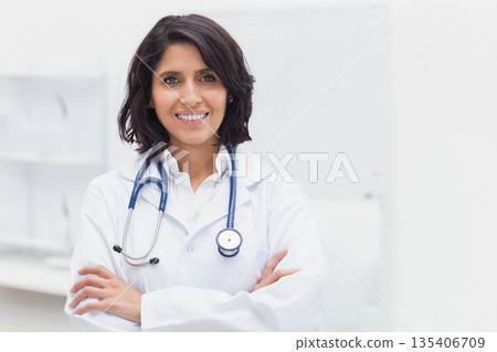 Female doctor standing confidently in bright medical office, wearing lab coat and stethoscope Female doctor standing confidently in bright medical office, wearing lab coat and stethoscope 135406709