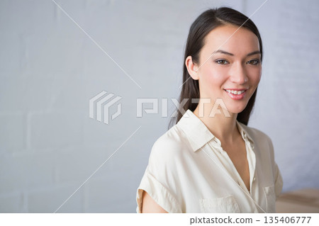 Asian woman smiling, wearing blouse and standing before painted brick wall in studio, copy space Asian woman smiling, wearing blouse and standing before painted brick wall in studio, copy space 135406777