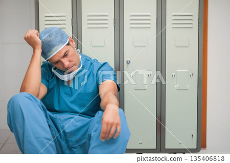 Hispanic male surgeon leaning against lockers in locker room, wearing scrubs and bouffant cap 135406818